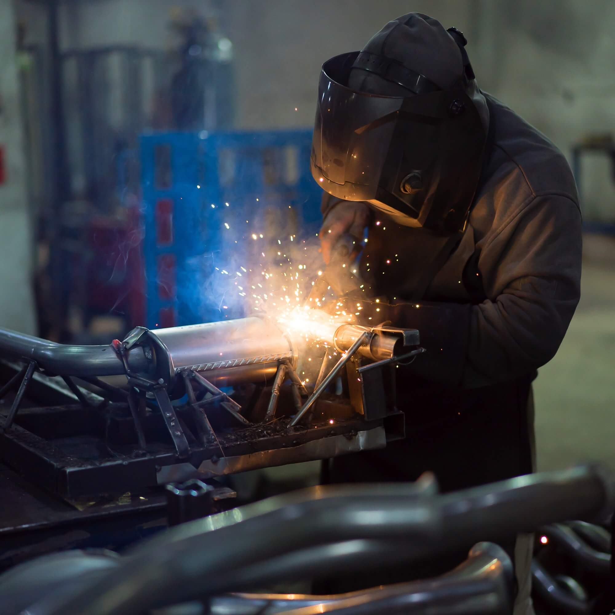 Worker welding exhaust pipes pieces together 1.jpg